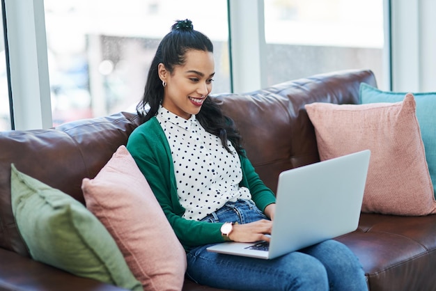 Alguns dos melhores trabalhos acontecem longe de uma mesa foto de uma jovem usando um laptop enquanto relaxa em um sofá