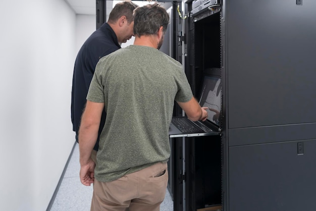 Alguns engenheiros de servidor cooperam em data centers de alta tecnologia. Equipe de técnicos atualizando hardware inspecionando o desempenho do sistema na sala do supercomputador ou fazenda de mineração de criptomoedas.