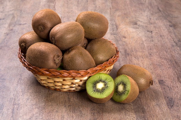 Alguns kiwis em uma cesta sobre uma superfície de madeira. frutas frescas