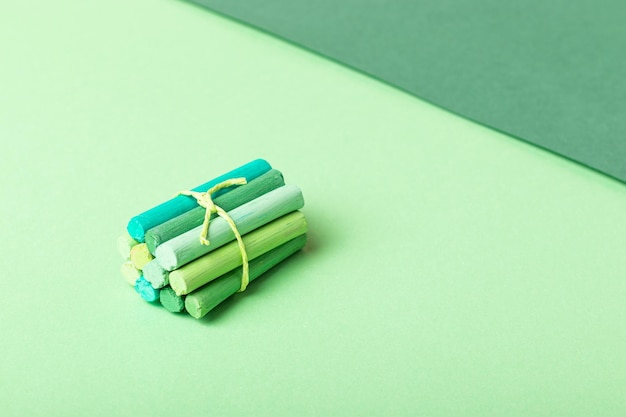 Alguns lápis pastel amarrados com uma fita em papel verde pastel. Paleta verde