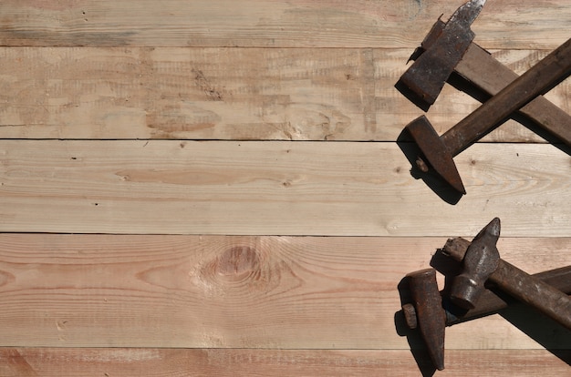 Alguns martelos enferrujados encontra-se em uma mesa de madeira em uma oficina