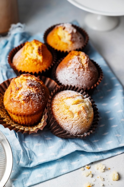 Alguns muffins em um pano azul com um que tem coalhada de limão.