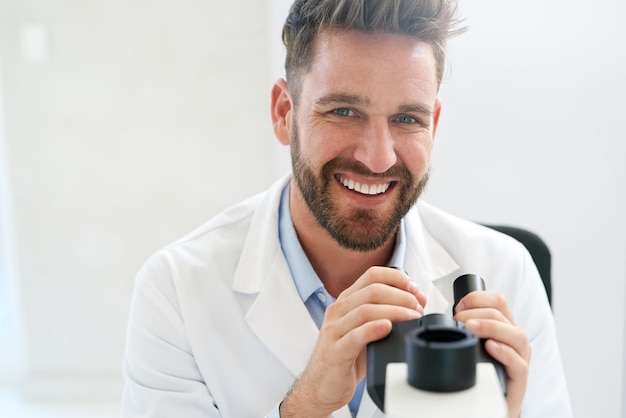 Alguns o chamariam de cientista visionário Retrato de um cientista masculino usando um microscópio em um laboratório