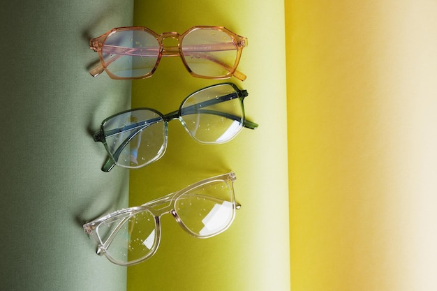Foto alguns óculos diferentes em papel enrolado, fundo geométrico, cores verdes, fundo cinza, conceito de teste de visão, acessórios de moda elegantes e bonitos na loja de ótica