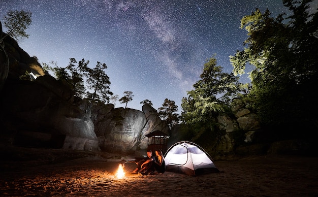 Alguns turistas descansando ao lado do acampamento, barraca da fogueira à noite