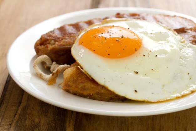 Alheira frita con huevo en plato blanco