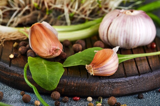 Alho, cebolinha, rudimentos e ervilhas de pimenta em uma madeira