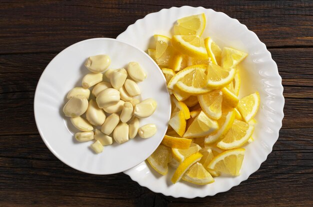 Alho descascado e limão fatiado no prato na mesa de madeira escura vista superior Alimentação saudável