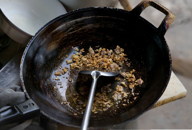 Alho frito em panela de metal preto com concha na cozinha de estilo chinês