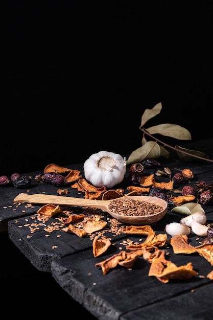 Alho, frutos secos e sementes na superfície rústica escura. Foto artística de alho e frutas secas na mesa preta velha, filmado em estilo ciaroscurro baixa chave