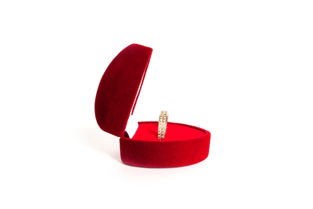 Aliança de ouro em uma caixa de joias vermelha em forma de coração isolada em um fundo branco. Foto de alta qualidade