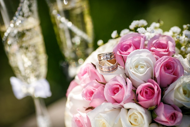 Alianças de casamento com rosas e taças de champanhe