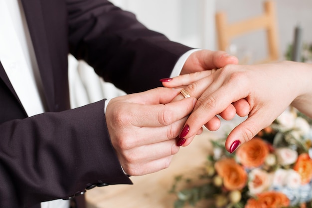 Alianças de casamento e mãos dos noivos jovem casal de noivos