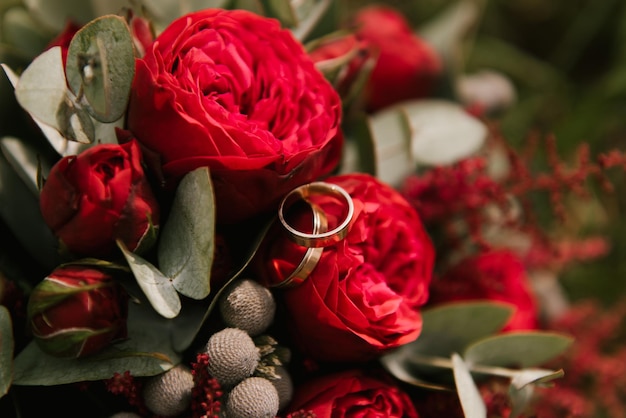 Alianças de casamento em um buquê de flores rosa vermelha foco suave