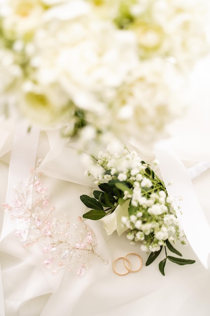 Alianças de casamento junto com joias e uma flor na lapela no véu