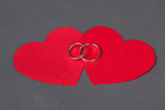 Alianças de casamento no coração vermelho sobre fundo cinza