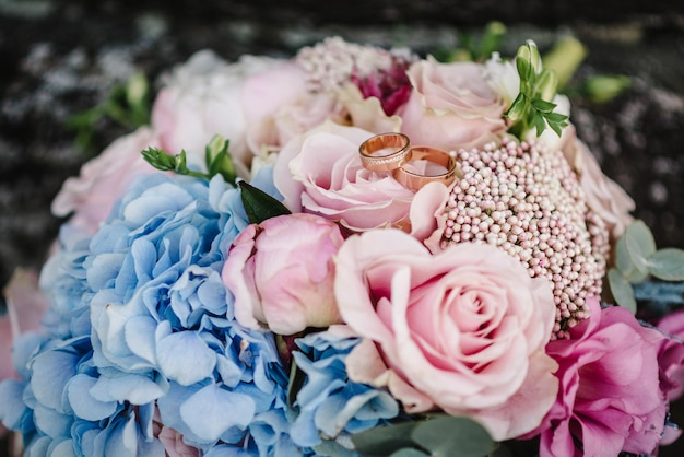 Alianças de casamento noiva e noivo no buquê de noiva de fundo com flores rosas e hortaliças