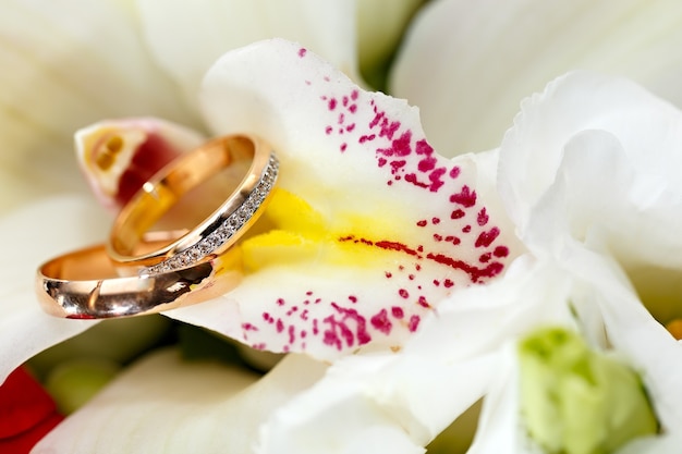 Alianças de ouro em um buquê de flores para a noiva