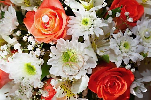 Alianças de ouro em um buquê de flores para a noiva