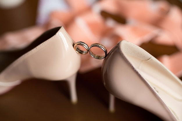 Alianças de ouro entre os sapatos de casamento da noiva