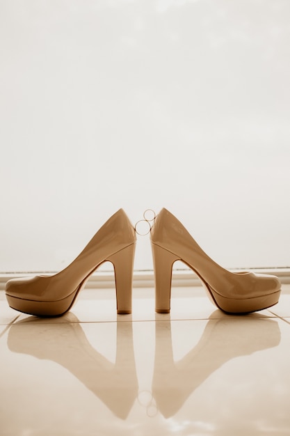 Foto alianças de ouro entre um par de sapatos de salto alto branco