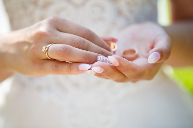 Alianças de ouro nas mãos de noivos no dia do casamento