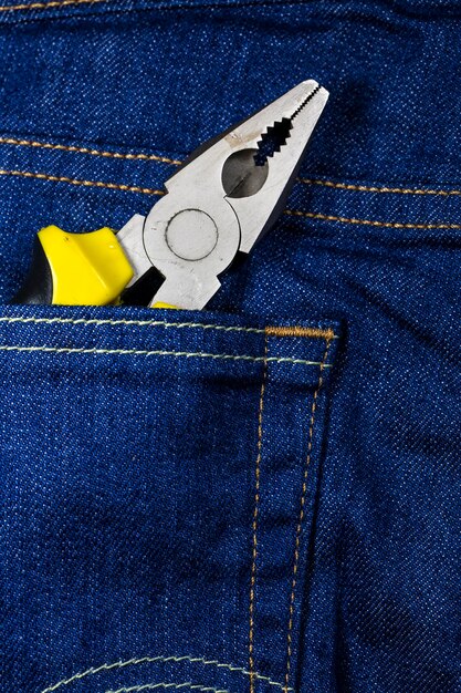 Alicate amarelo em um bolso de jeans azul. Nippers Ferramentas para reparos em geral. Construção