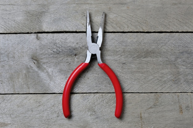 Alicates con asas rojas sobre una mesa de madera