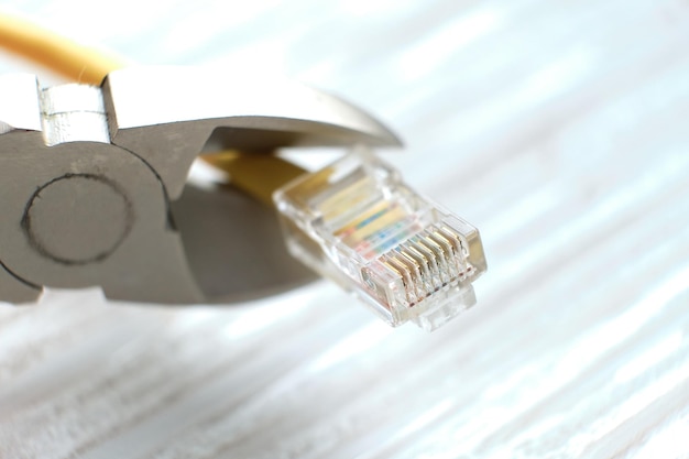 Alicates y cable de internet en un fondo gris el concepto de apagar internet por cable por falta de pago