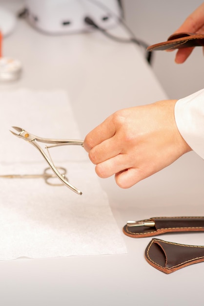 Alicates de uñas en la mano del maestro de manicura femenino poniendo la toalla antes del cuidado de las uñas en el salón de manicura.