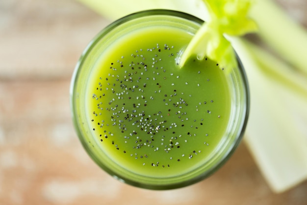 alimentação saudável, alimentos orgânicos e conceito de dieta - close-up de suco verde fresco com sementes de chia e aipo na mesa