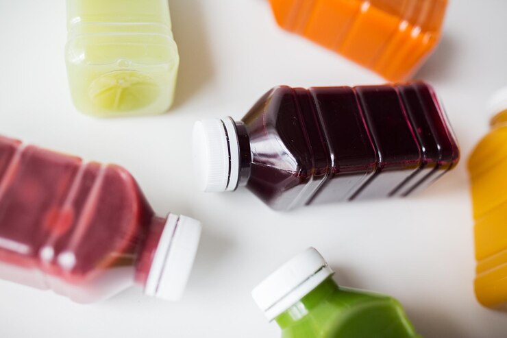 Foto alimentação saudável, bebidas, dieta e conceito de desintoxicação - fechamento de garrafas plásticas com diferentes sucos de frutas ou vegetais em branco