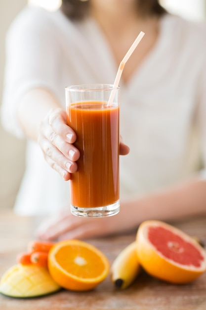 Alimentação saudável, comida, dieta e conceito de pessoas - close-up de mãos de mulher com frutas e suco fresco sentado à mesa