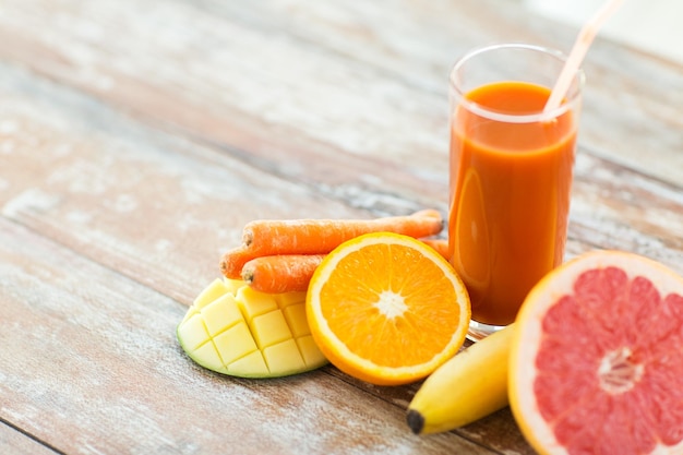 alimentação saudável, comida e conceito de dieta - close-up de copo de suco fresco e frutas na mesa