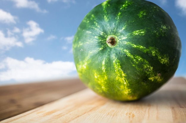 alimentação saudável, comida, frutas e conceito vegetariano - close-up de melancia na tábua de madeira sobre fundo de céu azul