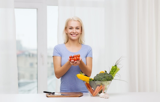 alimentação saudável, culinária, comida vegetariana, dieta e conceito de pessoas - jovem sorridente com tigela de legumes em casa