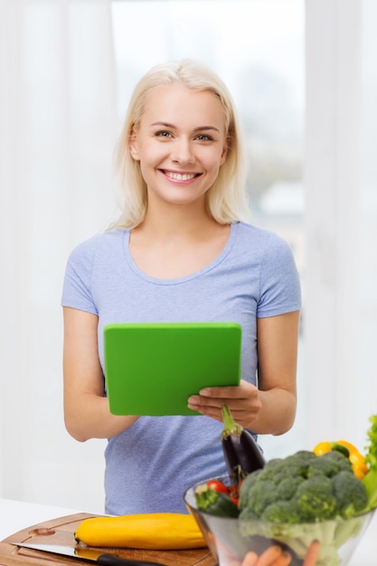 alimentação saudável, culinária, comida vegetariana, tecnologia e conceito de pessoas - jovem sorridente com computador tablet pc e tigela de legumes em casa