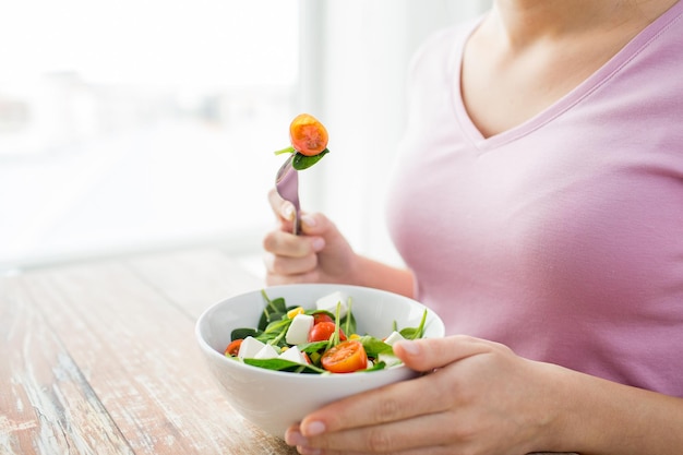 alimentação saudável, dieta e conceito de pessoas - close-up de jovem comendo salada de legumes em casa