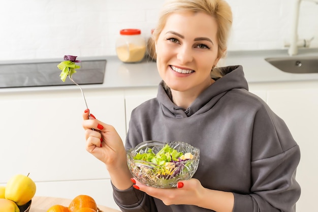 alimentação saudável, dieta e conceito de pessoas - close-up de jovem comendo salada de legumes em casa.