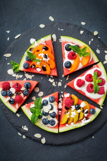 Alimentação saudável, dieta e nutrição conceito sazonal de verão Pizza de melancia com frutas frutas iogurte feta queijo em uma mesa Vista superior plana de fundo