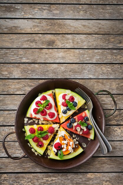 Alimentação saudável dieta e nutrição conceito sazonal de verão Pizza de melancia com frutas frutas iogurte queijo feta em uma mesa de madeira rústica Vista superior plana leiga espaço de cópia