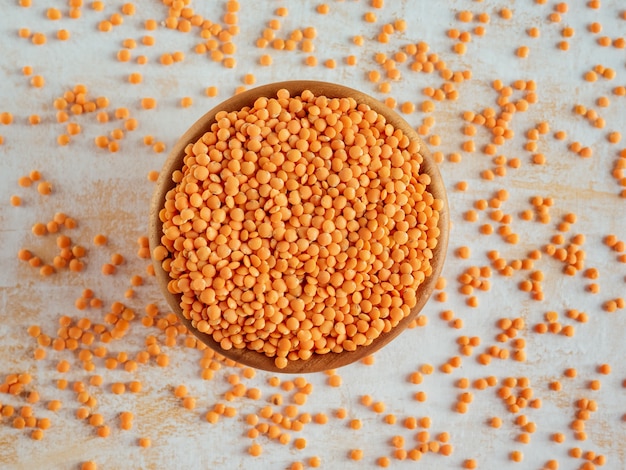 Alimentação saudável e dietética. Tigela de lentilha vermelha crua em fundo branco de madeira. Vista do topo. Postura plana. Masoor Dal ou lentilhas de laranja canadenses. Super comida vegetariana.