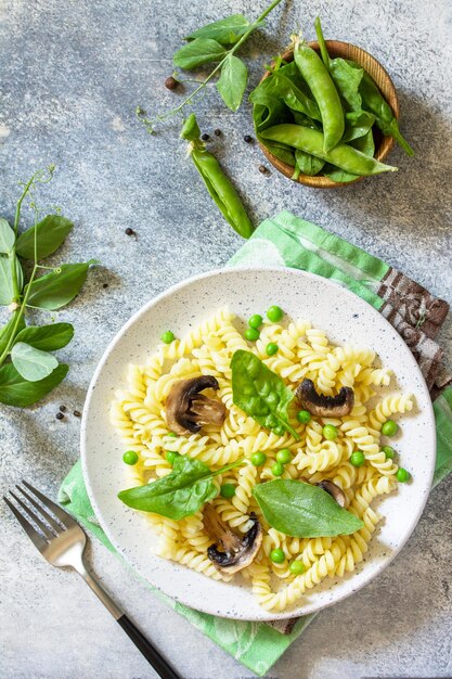 Alimentação saudável Macarrão fusilli com cogumelos espinafre e ervilhas verdes Vista superior plana Copiar espaço