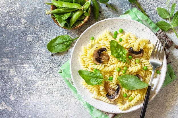 Alimentação saudável Macarrão fusilli com cogumelos espinafre e ervilhas verdes Vista superior plana Copiar espaço