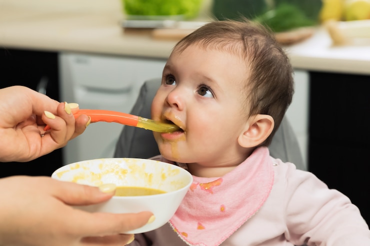 Foto alimentación. adorable bebé niño comiendo con una cuchara en una silla para niños.
