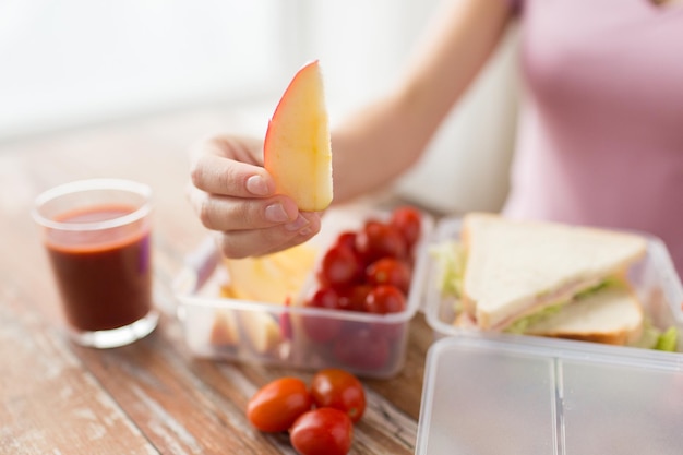 alimentación saludable, almacenamiento, dieta y concepto de personas: cierre de una mujer con comida en un recipiente de plástico en la cocina de casa