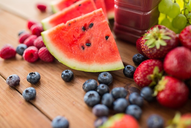 alimentación saludable, comida, dieta y concepto vegetariano - botella con jugo de frutas y bayas o batido en una mesa de madera