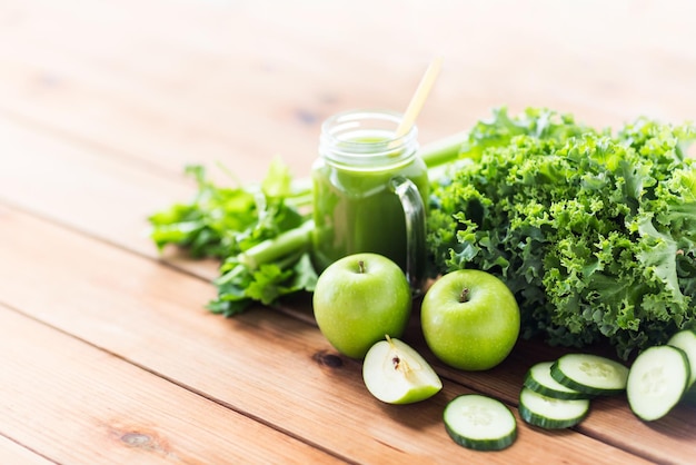 alimentación saludable, comida, dieta y concepto vegetariano - jarra de vidrio con jugo verde, frutas y verduras en una mesa de madera