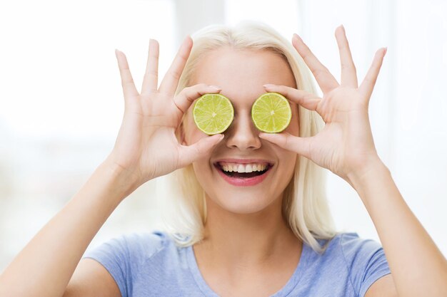 alimentación saludable, comida orgánica, dieta de frutas, cómic y concepto de personas - mujer feliz divirtiéndose y cubriendo sus ojos con rodajas de lima