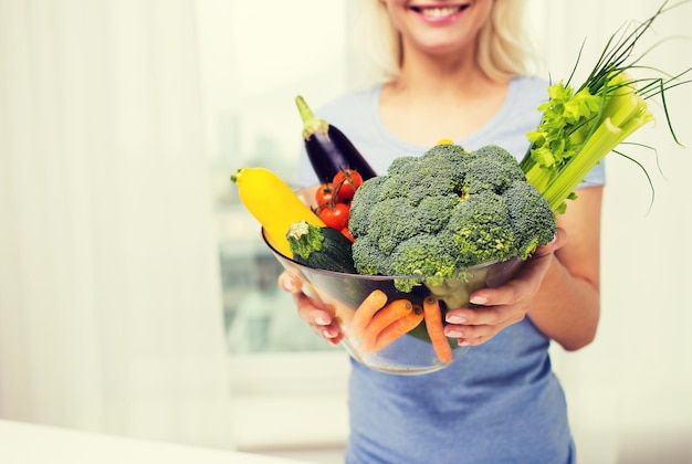 alimentación saludable, comida vegetariana, dieta y concepto de personas - cerca de una mujer sosteniendo verduras en un tazón